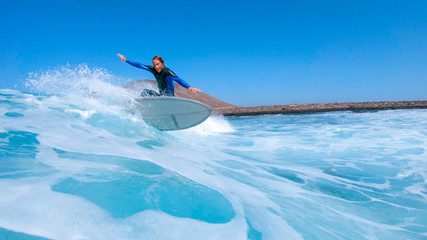 LOW ANGLE: Pro male surfer carves a beautiful turquoise wave near scenic Lobos. - obrazy, fototapety, plakaty