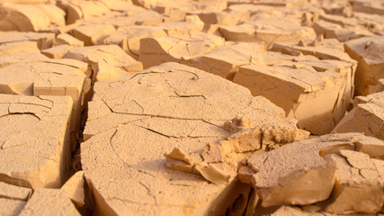 MACRO, DOF: Small particles of mud breaking off of larger pieces of dry soil.