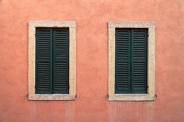 Fototapeta na wymiar Two windows with closed shutters.