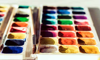 Watercolor paint and brushes well used on white wooden table with copy space for text.