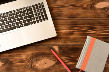 Laptop, notebook and pen on wooden table. Various office supplies on wooden background.