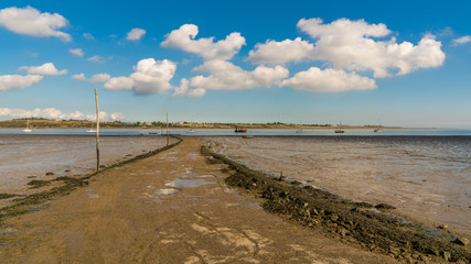 Obraz premium Boats in the Oare Marshes with the Isle of Sheppey in the background, near Faversham, Kent, England, UK