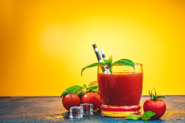 Red cocktail with tomato juice between tomatoes, fresh basil and ice.