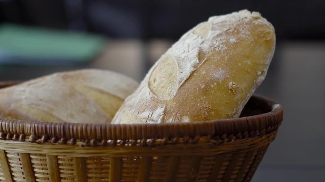 a wicker basket on a table with two loaves of crusty sourdough bread