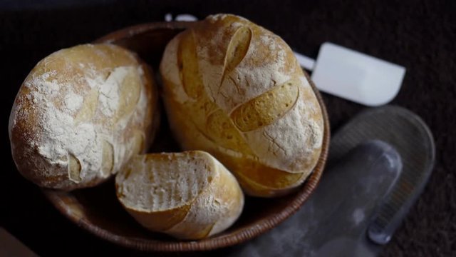 a boule and batard of crusty golden brown sourdough with an oven glove and a spatula