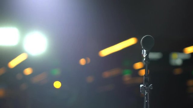 Microphone on stand on stage of bokeh of lights on background, auditorium, close-up. Waiting for performances. seminar speaker conference competition concert voice singer speech artist public speaking