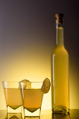 Limoncello in glass cups and a bottle on a beautiful background