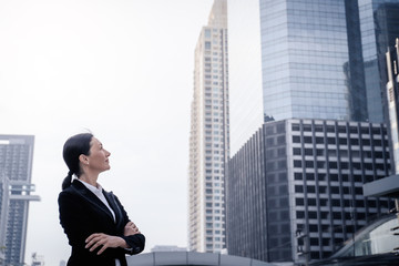 Fototapeta na wymiar Successful senior businesswoman leader standing and looking forward over modern building background
