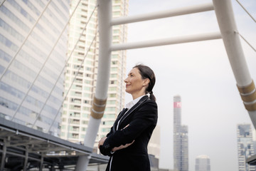 Successful senior caucasian businesswoman leader standing over modern building background