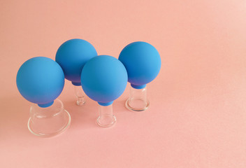 blue cosmetic vacuum jars of different sizes made of glass and rubber on pink background