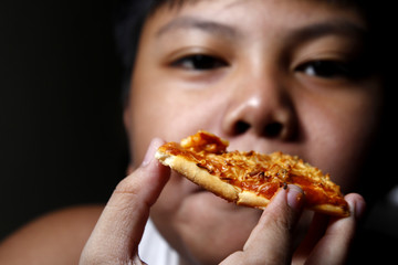 Young Asian boy eating a slice of pizza