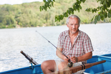 Geduldiger Senior Mann im Boot beim Angeln