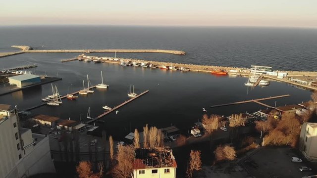 Pan aerial shot of Old Town Constanta City and harbor, Romania, Europe. Shot in spring during sunset and Golden Hour, revealing the Black Sea and the architecture while seagulls fly