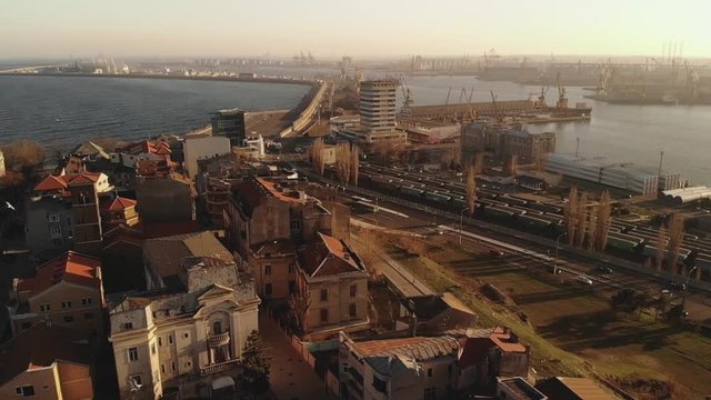 Pan aerial shot of Old Town Constanta City and harbor, Romania, Europe. Shot in spring during sunset and Golden Hour, revealing the Black Sea and the architecture while seagulls fly