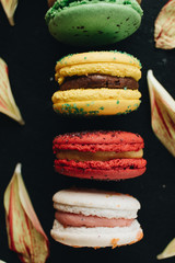 Composition of delicious bright macaroons and floral petals, sweet dessert