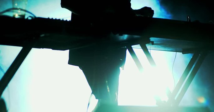 keyboard player performing on stage under flashing lights in slow motion.
