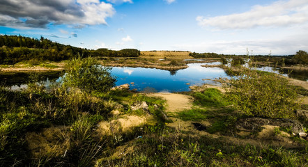 Sandy hills. Lake in the Sandy canyon. Warm colors background. Yellow sandstone textured mountain, white thin sand dune, bright sky. Sunshine landscape