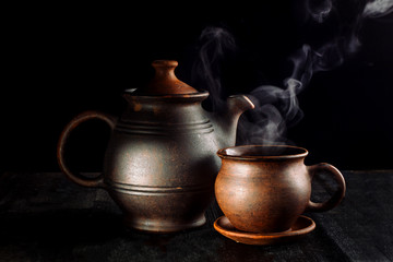 Tea cup and teapot, on a wooden table, beautiful sunshine and black background.