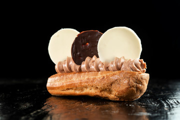 Choux pastry, with cream and chocolate on a black background.