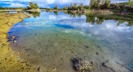 Sandy hills. Lake in the Sandy canyon. Warm colors background. Yellow sandstone textured mountain, white thin sand dune, bright sky. Sunshine landscape