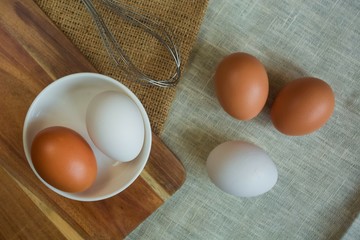 preparation for whipping eggs, whisk, white and orange eggs lie on natural light fabric