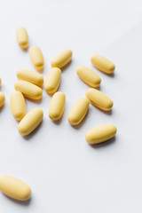 Fototapeta na wymiar Scatterded yellow pills on white background