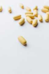 Fototapeta na wymiar Scatterded yellow pills on white background