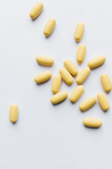 Scatterded yellow pills on white background