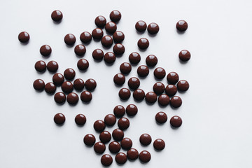 Flat lay of delicious sweet chocolate drops on white background
