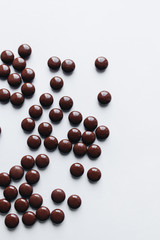 Flat lay of delicious sweet chocolate drops on white background