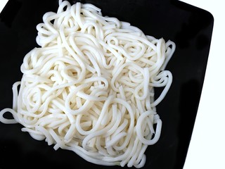 Top view of white noodle or Udon on black plate isolated on white background