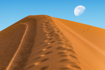 huge sand dune on the background of the sky with a moon on the horizon