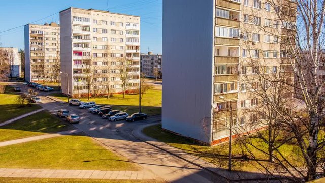 Old soviet block housing in mid day sun with people walking 