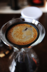Alternative manual coffee brewing in black porous japonic ceramic paperless dripper filter. Glass jug. Closeup top view