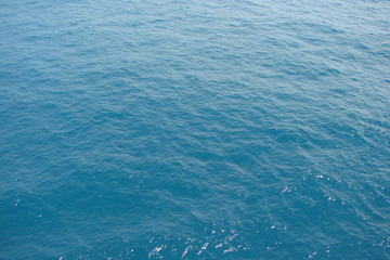 A view from the deck of the ship on a variety of shades of blue color of the sea surface under the rays of the sun, which are reflected from a small ripple.