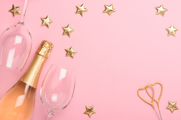 Champagne with glasses heart shaped sparklers and golden stars on pink background