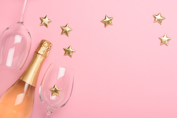 Champagne with glasses and golden stars on pink background