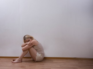 Naklejka premium woman sitting on the floor and zakryvaet face with his hands.