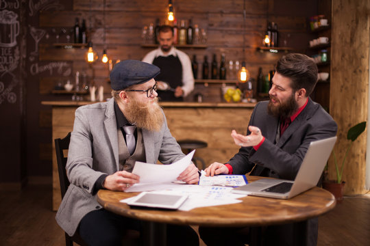Two bearded economists having a business meeting in a coffee shop