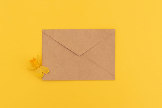 Kraft Envelope On Yellow Background And Beautiful Daffodil Flowers