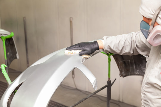 Preparation for painting a car element using emery sponge by a service technician leveling out before applying a primer after damage to a part of the body in an accident in the vehicle workshop