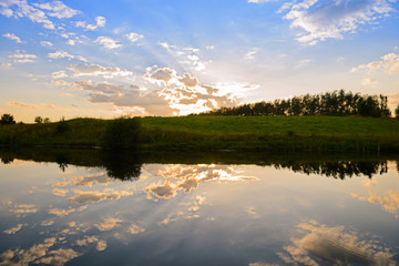 evening summer landscape with reflection of clouds in a pond