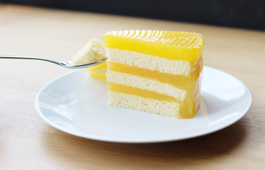 Orange cake in the plate on wooden table background