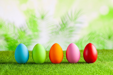 Happy Easter - Colored eggs on grass and green abstract background