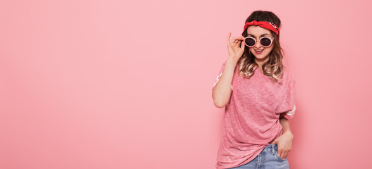 Portrait of hipster girl in glasses on pink background