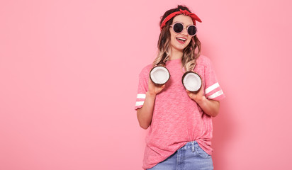 Obraz premium Portrait of a girl with coconuts, on a pink background