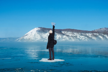 Back of a man holding triangle shaped ice standing on ice floes floating in river in winter with background of snow mountain. Concept of human desire for more © tarapatta