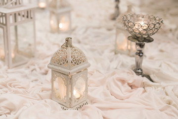 Pale toned candle holders on wrinkled cloths, wedding decorations