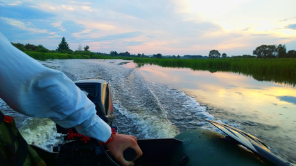 Movement on a rubber boat with a motor on the evening river after fishing.