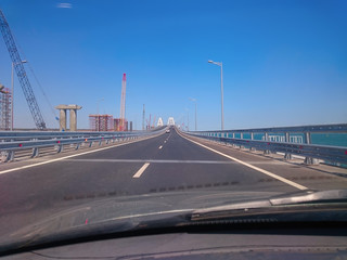 Fototapeta na wymiar View through the windshield of a moving car. Crimea, Russia - June, 8, 2018: Travel on the Crimean bridge during its construction. View from the car